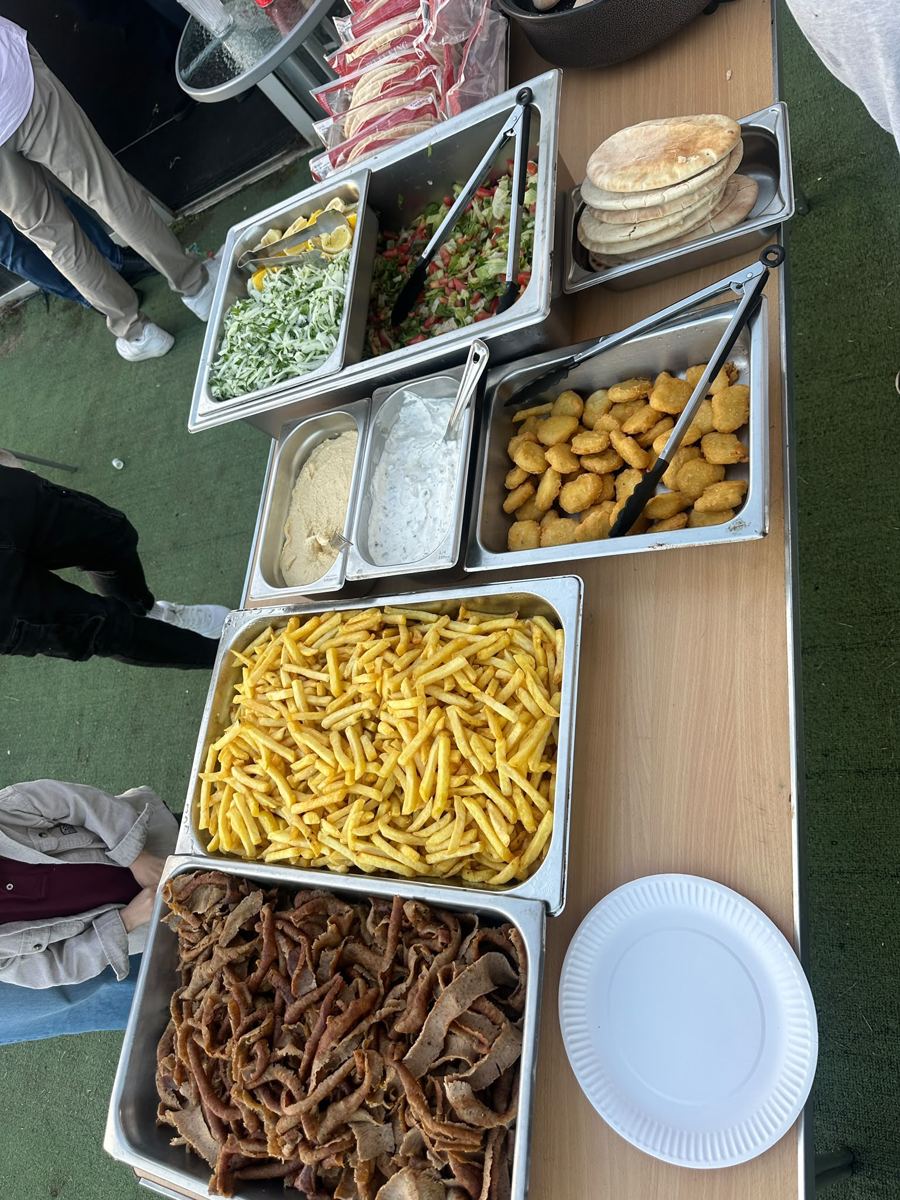 Catering trays of döner meat, chips, salad, cacik, hummus and pita bread